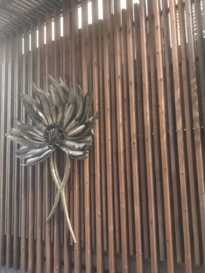 A close-up of a wooden screen wall, enhanced with a beautiful metallic flower artifact. This shows how we combine structural elements with decor.