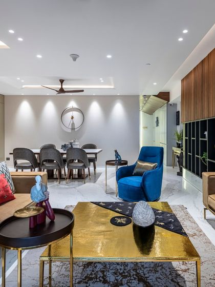 A complete view of the Filigree House living and dining area. The space is unified by a consistent palette of neutral tones, rich woods, and a striking pop of royal blue, creating a cohesive and sophisticated open-plan environment.