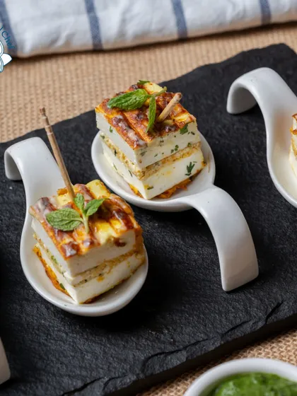 My Rozali Stuffed Paneer Sandwiches are a gourmet delight. The paneer is layered with a flavorful green chutney and grilled, then served on tasting spoons for an elegant presentation.