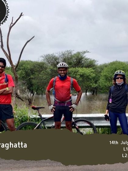 Three riders pose for a photo during our Hesaraghatta ride, with a flooded lake behind them. The monsoon season adds an extra layer of adventure.