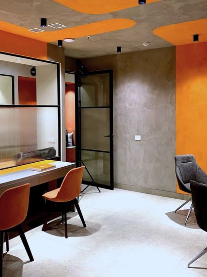 The faculty lounge in the basement uses a mix of comfortable seating and bold orange color blocking on the walls and ceiling to create a dynamic yet relaxing space.