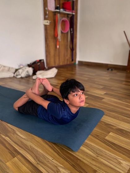 This young yogi is practicing Dhanurasana, or bow pose, which is excellent for strengthening the back and improving posture. In my classes, we focus on building strength and body awareness in a safe and playful way.