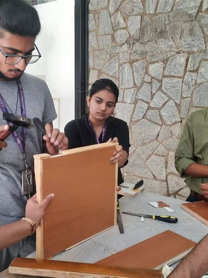 Budding architects from BMS College of Architecture learning basic furniture construction. Here, they are using hammers and nails to assemble a frame.