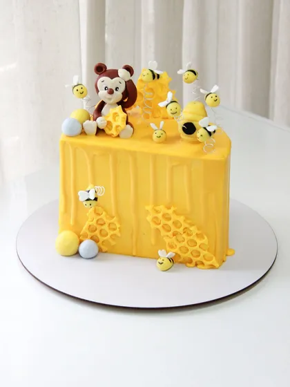 A "hunny" of a half birthday cake, featuring a bear and lots of busy bees around a honeycomb.