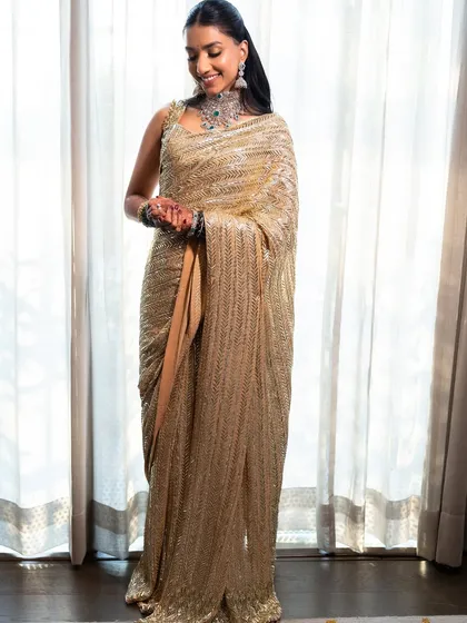 A full-length view of the golden saree look. The entire ensemble is the epitome of wedding guest glamour.
