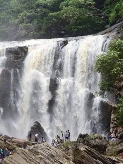 Sathodi Falls in its full glory, with fellow adventurers enjoying the view from the base. This is a key destination on our Yallapura trip, known for its wide, picturesque cascade.