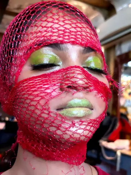 A creative makeup look from a class demo, using a net and bold colours to create an avant-garde effect.