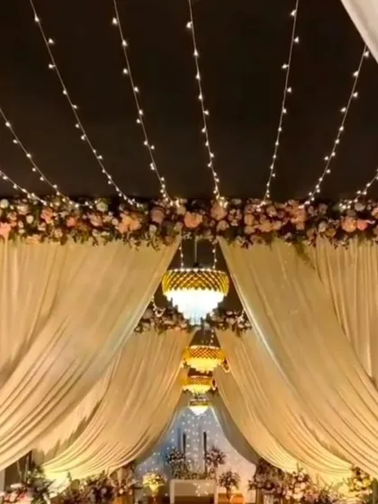An enchanting wedding mandap setup with a ceiling of fairy lights, elegant white drapes, and beautiful chandeliers, creating a magical ambiance for the ceremony.