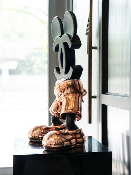 A side view of the "Chanel Mickey" sculpture, showing the iconic Chanel logo replacing Mickey's head.