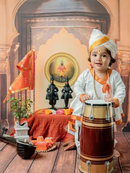 A joyful toddler stands with the dhol, his smile lighting up the frame. This is a perfect example of a happy, interactive portrait.