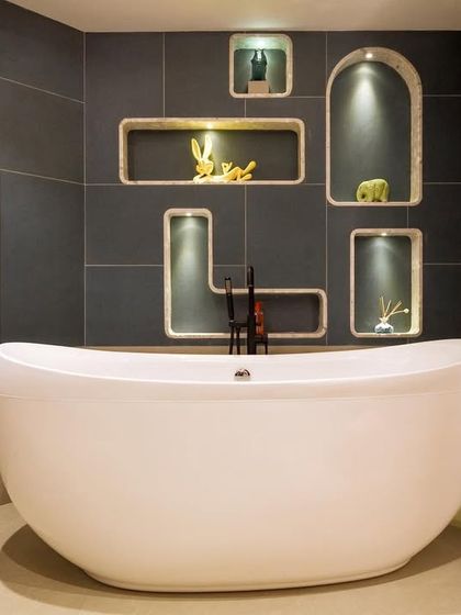 A dreamy, bubble-inspired bathroom designed for a young client. The freestanding tub is set against a dark tiled wall with custom-lit, bubble-shaped niches for a playful yet sophisticated look.