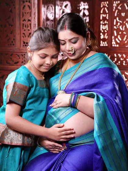 Celebrating the journey to motherhood with our traditional Maharashtrian maternity shoot. Here, a mother-to-be and her daughter share a quiet moment, beautifully dressed in matching Paithani-style sarees.