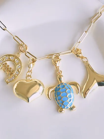 Charms that speak louder than words. This custom necklace features a good luck horseshoe, a heart, a turtle, and a whale tail. What's your story?