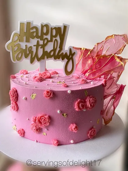 A pretty pink birthday cake with piped rosettes and an elegant rice paper sail. The gold leaf adds a touch of luxury.