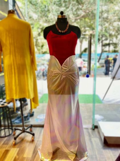 A show-stopping off-shoulder gown designed for the red carpet. The vibrant red velvet top contrasts beautifully with the iridescent, shimmering skirt, creating a silhouette that is both bold and elegant.