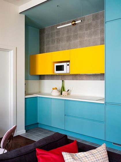 This kitchen proves that bold colors can work beautifully in small spaces. The combination of bright yellow and blue cabinets, along with a simple grey tile backsplash, creates a joyful and energetic atmosphere.