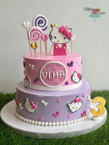 A sweet two-tiered Hello Kitty cake designed for a third birthday. This whipped cream cake is decorated with handmade fondant bows, hearts, and lollipops, creating a perfectly charming and girly theme.