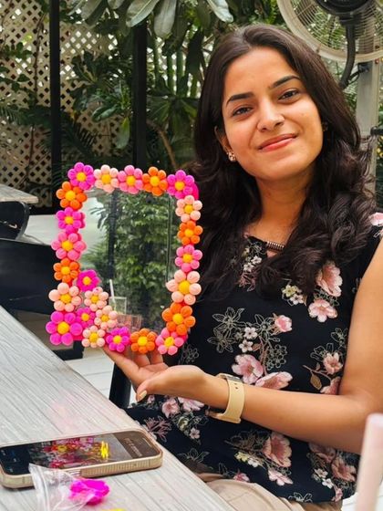 A participant with the vibrant, floral-themed mirror she created using clay. Our mirror decorating workshops are a fun way to add a pop of color to your room.