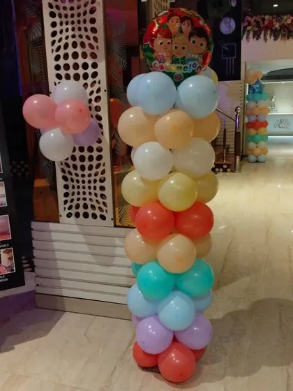 A colorful balloon pillar with a Cocomelon-themed foil balloon on top, a simple yet effective decoration for a kid's party.