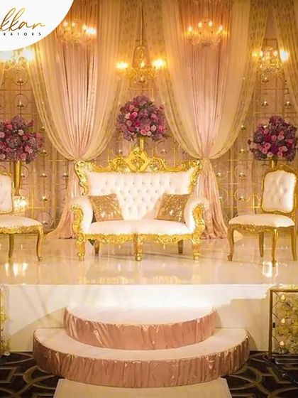 A classic and elegant reception stage with a pink and gold theme. The royal seating and soft, draped backdrop create a timeless and romantic atmosphere.