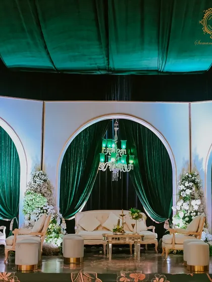 A full view of the elegant lounge area on the stage, providing a luxurious and comfortable space for the family against a backdrop of emerald drapes and chandeliers.