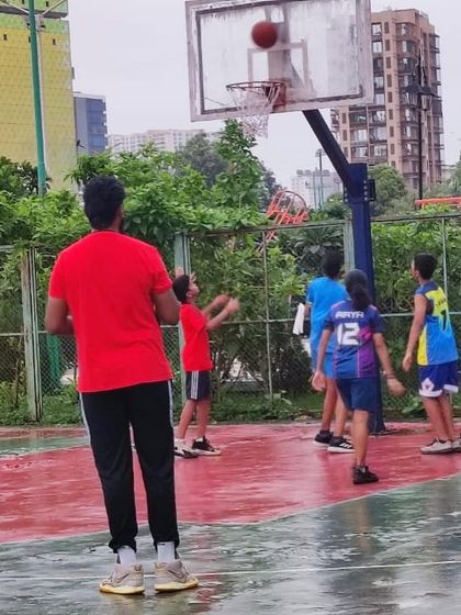 A coach watches as players continue their shooting drills in the rain. This dedication is what builds champions.