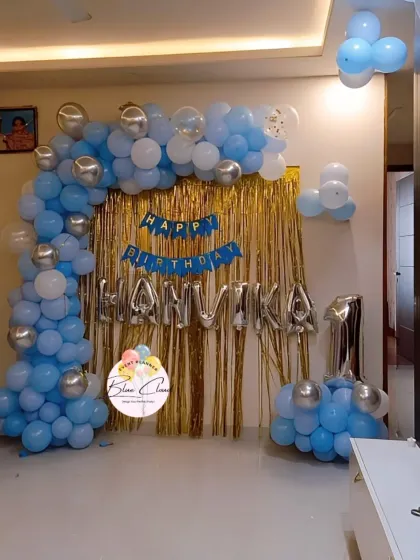 A balloon arch in blue, white, and silver with a gold shimmer curtain for a 14th birthday.