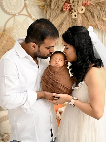 A tender moment of parental love. Both mother and father gently kiss their newborn's head, a beautiful gesture of affection captured in a bright and warm setting.