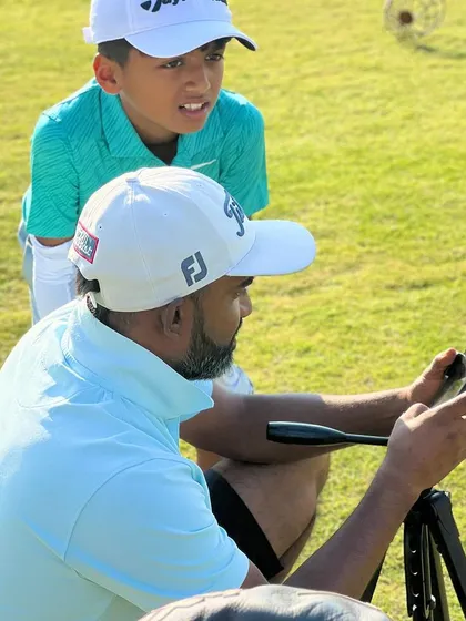 A close-up of a coach and a young player reviewing swing video. Even at a young age, we introduce players to the concept of using technology to understand their own game.