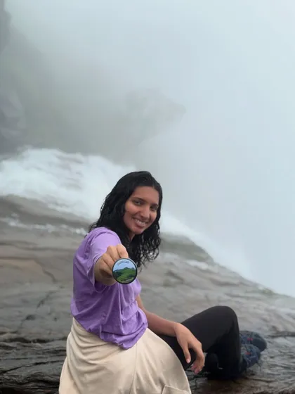 A trekker proudly shows off her Bandaje badge at the top of the falls.