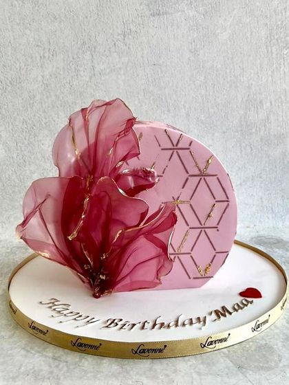 A modern and artistic cake for a mother's birthday. The design features a geometric pattern and a large, abstract wafer paper flower.