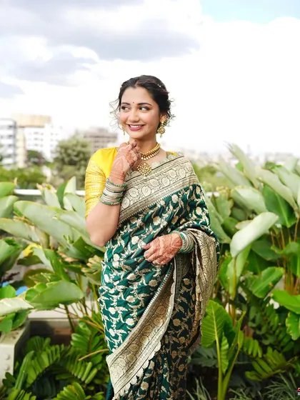 A candid moment in a beautiful outdoor setting. The natural light makes her skin look even more radiant and her green saree even more vibrant.