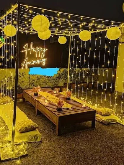 I can create a cozy and intimate cabana on your terrace or lawn. This anniversary setup is built with a curtain of warm fairy lights and paper lanterns, providing a perfect private space for a romantic dinner.