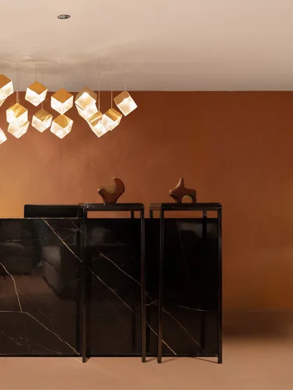 A detail shot of the reception area, focusing on the sculptural art pieces and the cluster of cubic pendant lights. These elements add a layer of sophistication and artistic flair to the corporate environment.