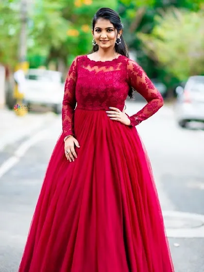 A confident and elegant pose. This full-length view shows the A-line silhouette and beautiful lace sleeves of the red gown, a timeless choice for any celebration.