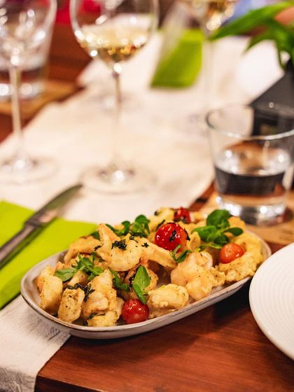 A platter of our crispy fried appetizers, garnished with fresh basil and cherry tomatoes. These small plates are perfect for sharing while waiting for the main event.