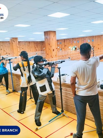 An instructor guides a pistol shooter while others practice with rifles in the background. This shows our integrated training environment where different disciplines are taught simultaneously.