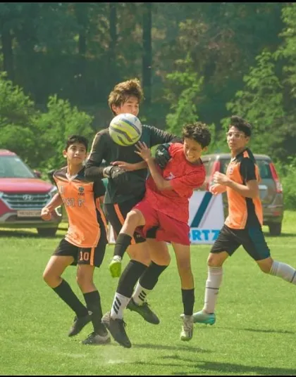 An aerial battle for the ball, showing the physical commitment of our U13 players.