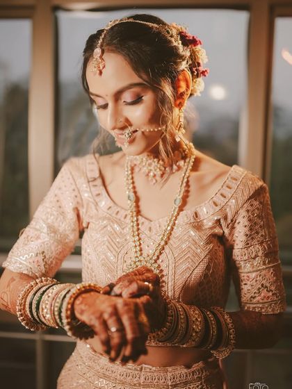 The bride getting ready, showcasing the intricate details of her lehenga and the soft, romantic hairstyle.