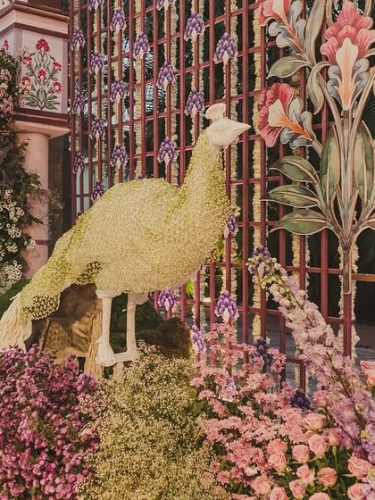 A close-up of the handcrafted peacock sculpture, covered in flowers, which was a key motif in our 'Vrindavan in Udaipur' wedding theme.