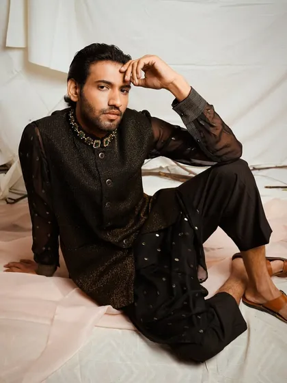 For this menswear look, I focused on creating a contemplative and sophisticated mood. The soft studio lighting highlights the texture of the sheer black kurta and the detailed embroidery on the bandhgala jacket, presenting a modern take on traditional Indian attire.
