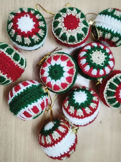 A collection of our handmade crochet Christmas baubles. Featuring classic red, green, and white patterns, these ornaments are a sustainable and charming alternative to plastic decorations.