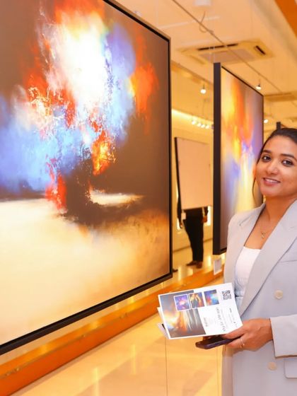 A guest admiring the large-scale, vibrant abstract paintings at the 'Mystic Mirage' exhibition. The gallery's lighting is designed to make the colors pop.