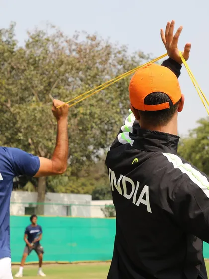 Guiding a player through shoulder strengthening exercises using a resistance band. This type of targeted training is essential for preventing common tennis injuries and maintaining shoulder health throughout a long tournament.