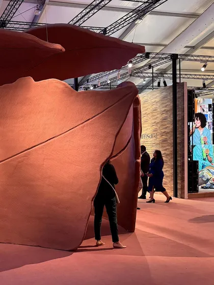 A visitor becomes part of the 'Terra' installation, dwarfed by the scale of the abstract leaf forms. The space is designed to be a metaphorical and poetic experience, rendering the emotion of homecoming and grounding in a quiet, familiar scene.