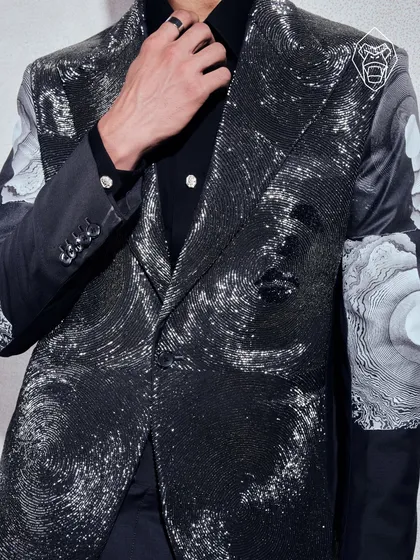 A detail of the Molten Metallic blazer, where hand-beading creates a liquid-metal effect that moves with light. This piece represents my more experimental, avant-garde approach to formalwear, designed for making a powerful impact.