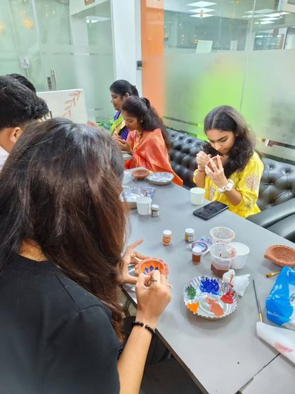 Everyone gets absorbed in their own artistic process. This close-up shows the focus and engagement that pottery painting inspires in a corporate team building setting.