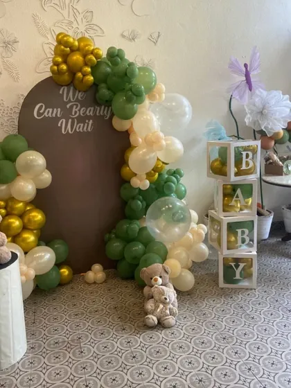 A "We Can Bearly Wait" baby shower theme. This cozy indoor setup features a beautiful balloon arrangement and cute teddy bear details.