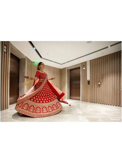 A joyful, twirling shot of the bride in her red lehenga, capturing her happiness and the grandeur of her outfit.