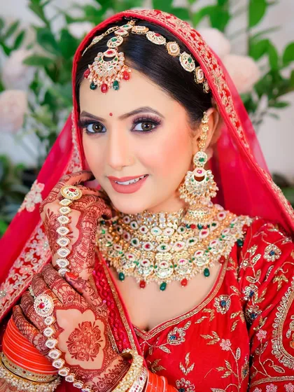 A beautiful, traditional bridal pose that showcases the complete look, from the headpiece to the henna on her hands.
